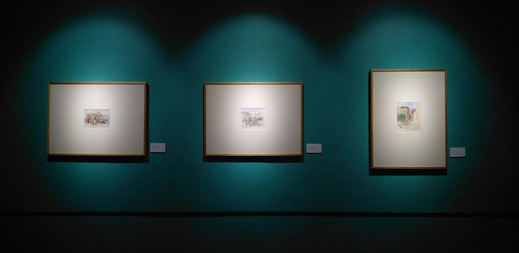 Framed artworks illuminated on a museum wall in Manila, capturing modern aesthetics.